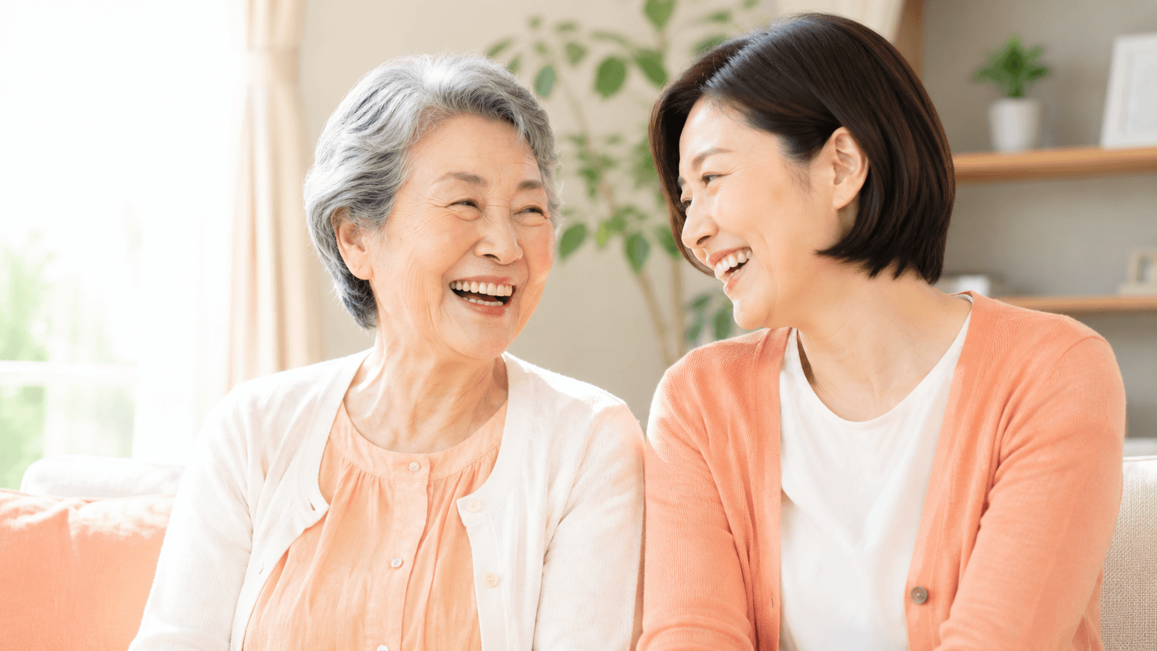 高齢の母親と40代の娘が向き合って笑い合っている